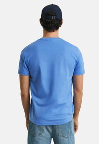T-shirt di cotone azzurro chiaro con maniche corte e scollatura a girocollo classica, abbinato a jeans di denim blu. Design semplice, senza motivi visibili.