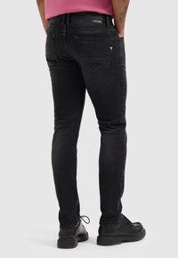 Zwarte slim-fit jeans van denim, met een middelhoge taille, twee achterzakken en een klein logo-label op de tailleband.