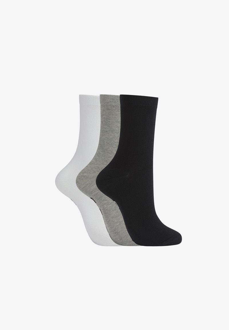 Trois paires de chaussettes unies de type crew en noir, gris et blanc, disposées côte à côte sur un fond blanc.