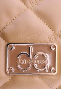 Bolso de mano acolchado color bronce, hecho de cuero suave, con una placa de logo plateada brillante con bordes redondeados y detalles de costura.