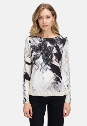Maglietta a maniche lunghe con un motivo astratto in bianco e nero. Realizzata in tessuto morbido con scollatura tonda e design aderente. Accenti neri all'orlo.