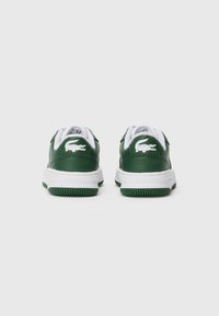 Baskets en cuir vert avec semelles et lacets blancs. Présentent un logo de crocodile blanc en relief au niveau du talon. Semelle extérieure en caoutchouc vert texturé.