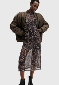 Φόρεμα με λεοπάρ σχέδιο και διάφανη υφή, συνδυασμένο με ένα ελαιόχρωμο bomber μπουφάν. Μαύρες μπότες μέχρι το αστράγαλο ολοκληρώνουν το ντύσιμο.