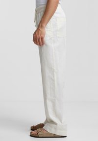 Byxor i linblandning i ljus krämfärg, med elastiskt midjeband och dragsko, sidofickor och en avslappnad passform med raka ben.
