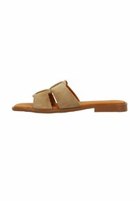 Beige instappers met twee brede, overlappende banden van zacht suede, een glad voetbed en een vlakke rubberen zool.