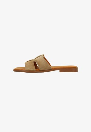 Beige slip-on sandals with two wide, overlapping straps in soft suede, a smooth footbed, and a flat rubber sole.