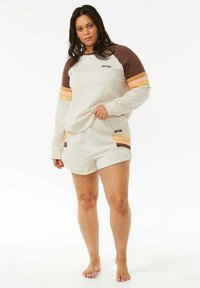 Sudadera gris claro con mangas a rayas marrones y naranjas, combinada con pantalones cortos a juego. Ambas prendas cuentan con detalles de logotipo. Textura de tela suave.