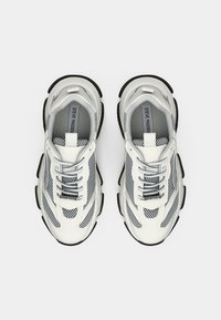 Baskets de sport blanches et grises avec des panneaux en mesh, système de laçage, semelle en caoutchouc et accents noirs, arborant un logo sur la semelle intérieure.