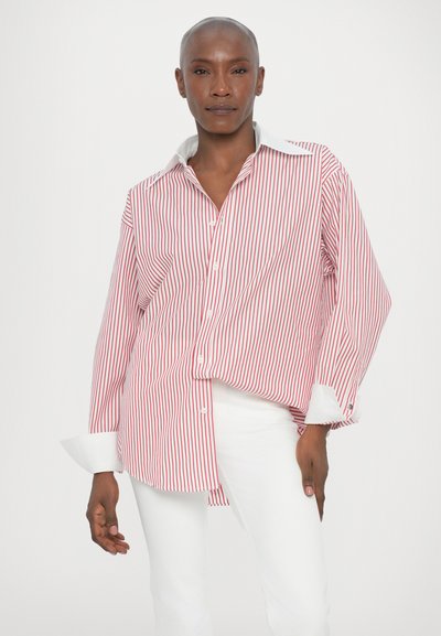Red and white striped button-up shirt with a folded collar, long sleeves, and white cuffs, paired with white trousers. Smooth texture.
