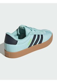 Jasnoniebieski tenis z płótna z czarnymi akcentami i trzema czarnymi paskami. Posiada teksturowany język i gumową podeszwę w kolorze beżowym. Logo w neonowej zieleni.