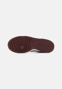 Nike tenisica s potplatom od tamnocrvene gume s teksturiranim kružnim i rebrastim uzorcima, te središnjim logotipom.