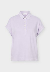 Ανοιχτό μοβ κοντομάνικο πόλο μπλουζάκι με γιακά και τέσσερα λευκά κουμπιά στο μπροστινό μέρος, απεικονίζεται σε λευκό φόντο.