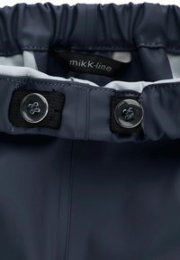 Mornarsko modra vodoodporna tkanina z elastičnim pasom, s črnimi velkro dodatki in prozornimi gumbi. Oznaka nosi napis "mikk-line."