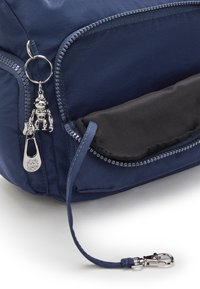 Marineblå stofpose med sølvhardware nøglering og lynlås. Har en sidelomme med sort foer og en dekorativ charme.