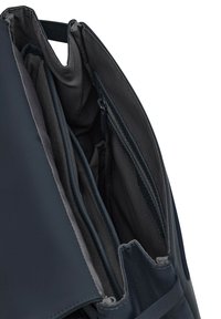 Donkerblauwe rugzakinterieur met meerdere compartimenten, voorzien van een zachte stoffen voering, soepele ritsen en elastische pockets voor organisatie.