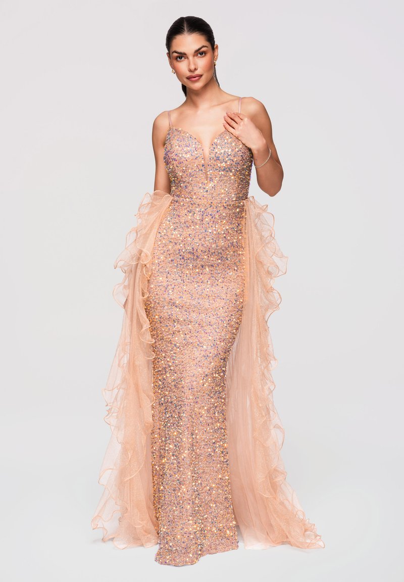 Femme portant une robe à sequins pêche scintillante avec un décolleté plongeant en V et des panneaux en tissu sheer à volants sur les côtés.