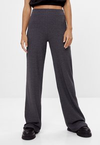 Grå ribbade vida byxor med hög midja, mjuk textur och avslappnad passform, i kombination med svarta robusta platåskor.