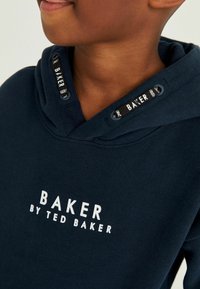 Felpa blu navy in cotone, con tasca a marsupio, polsini a coste e il logo bianco "BAKER by TED BAKER" sulla parte anteriore.