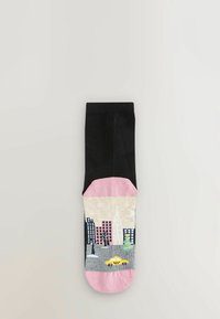Černé a růžové ponožky s designem městské krajiny, zahrnující budovy, žlutý taxi a strom na šedém pozadí. Hladký povrch.