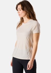 Maglietta atletica beige a maniche corte con scollo rotondo, dalla texture discreta e con cuciture a contrasto. Tessuto leggero e traspirante.