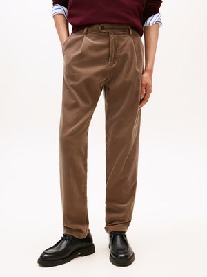 Pantalons en velours côtelé marron à coupe droite, avec des plis à l'avant et des poches latérales. Portés avec un pull bordeaux et des chaussures noires.