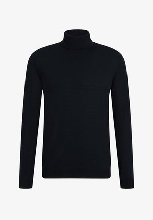 Marineblauer Rollkragenpullover mit Rippstruktur, kombiniert mit passenden schmal geschnittenen Hosen und weißen Sneakers, vor einem einfarbigen Hintergrund stehend.