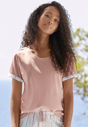Lyserød kortærmet t-shirt med rund hals og stribede bomuldsmanchetter, båret med lyse stribede pyjamasbukser med snor.