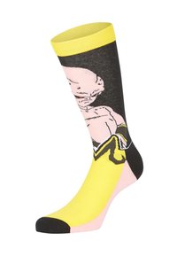Chaussette montante avec bord, talon et pied jaunes, présentant un personnage de dessin animé stylisé, chauve, au regard intense.