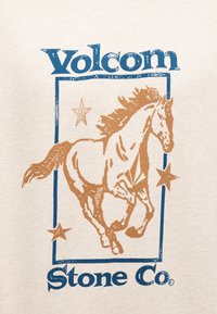 Ένα καφέ άλογο τρέχει μέσα σε ένα μπλε ορθογώνιο πλαίσιο με τρία αστέρια και το κείμενο "Volcom Stone Co." πάνω και κάτω.