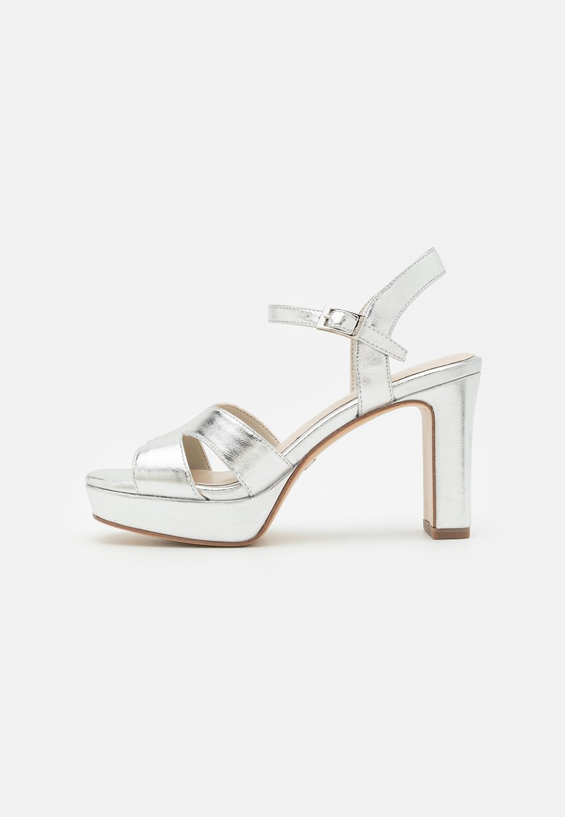 Silver metallic heeled sandals with a platform, featuring crisscross straps and a buckle closure, on a block heel. Smooth texture.