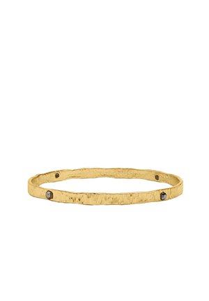 Złota bransoletka forma młotkowanego obręczy z małymi ciemnymi kamieniami szlachetnymi równomiernie rozmieszczonymi wokół obręczy na białym tle.