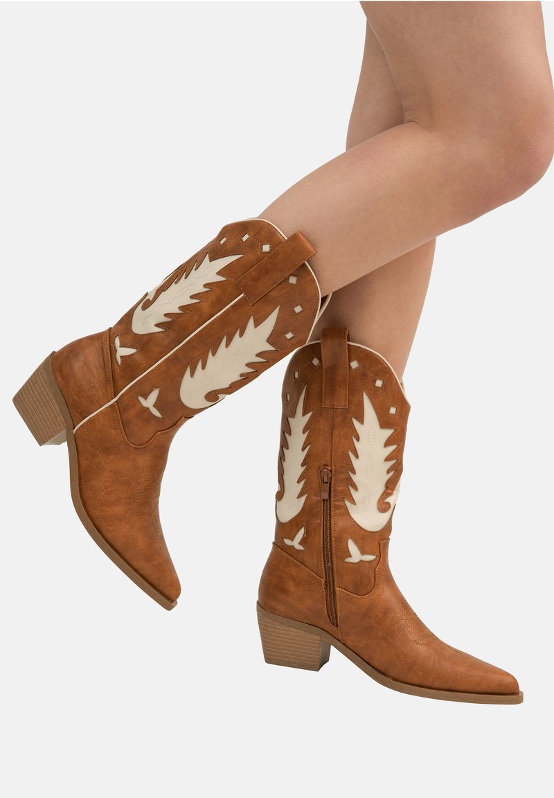 Bottes de cow-boy en simili cuir marron avec des accents blancs, à bout pointu, avec des détails texturés, des coutures décoratives et un talon bas empilé.
