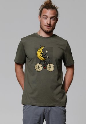 Olijfgroen katoenen T-shirt met een speelse banaangrafiek die op een fiets rijdt, gedetailleerd met lichtbruine wielen en rode accenten.