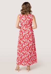 Maxi-jurk in het rood met een bloemenpatroon met roze en witte accenten, zonder mouwen, met een getailleerde taille en een uitlopende zoom.