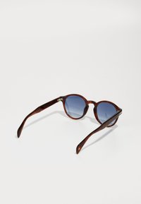 Lunettes de soleil rondes avec une monture en écaille de tortue et des verres dégradés bleus. Présente une texture lisse et de fines branches brunes avec des accents dorés.