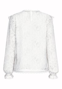 Hvit blondebluse med lange ermer, volanger på mansjettene og en bølget kant. Intrikat blomsterdesign dekker hele stoffet.