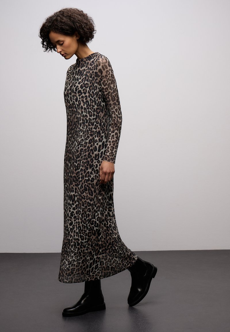 Šaty s leopardím potiskem dlouhý rukáv z průsvitné látky, s přiléhavým korzetem a splývavou sukní, doplněné černými kotníkovými botami.