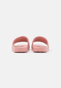 Sandali in gomma rosa con un design minimalista, apertura sul retro e una texture sottile. La suola è piatta con un leggero bordo rialzato per garantire aderenza.
