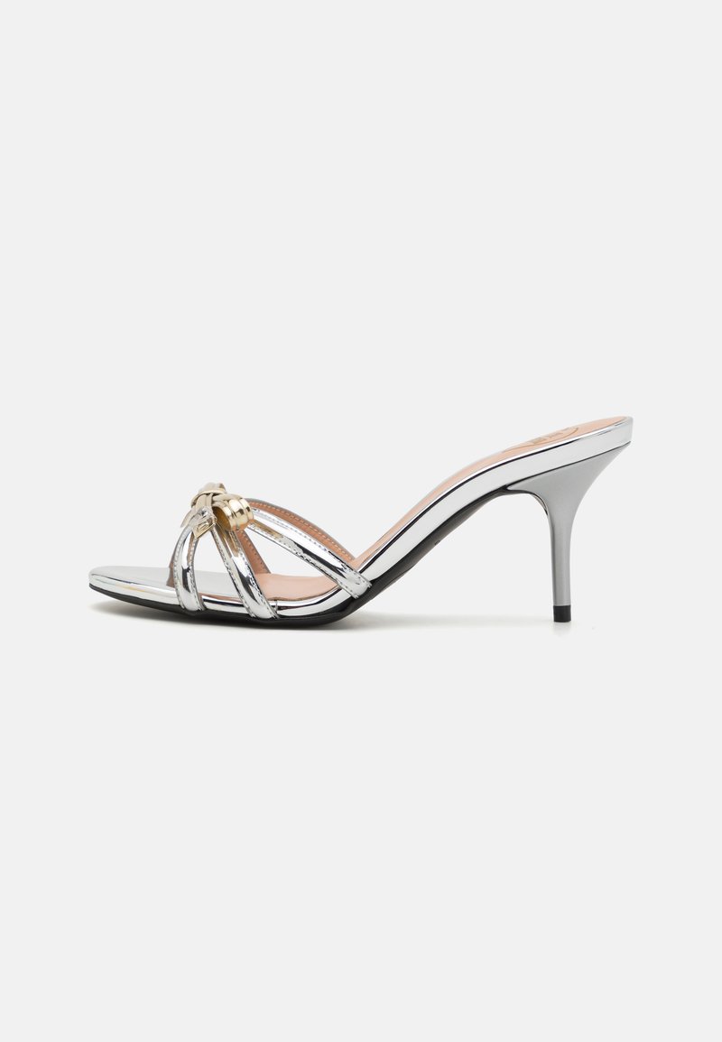 Metallic silver high-heel sandal with crisscross straps, gold accents, open toe, and a tapered stiletto heel. Smooth texture.