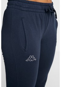 Marinblå sweatpants med dragsko i midjan, sidofickor och en vit logotyp på vänster lår. Tillverkade av ett mjukt tyg.