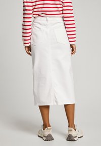 Hvite denim midi-skirt med to baklommer og rett snitt, sammen med en rød-og-hvitt stripete langermet skjorte og sneakers.