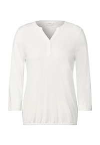 Bílý top s dlouhým rukávem vyrobený z hladkého materiálu, který má henley výstřih s jemným řadou knoflíků a elastický lem.