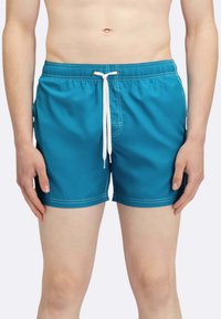 Pantaloni da mare blu con vita elasticizzata, cordino bianco, tasche laterali e cuciture bianche a contrasto. Lunghezza a metà coscia.