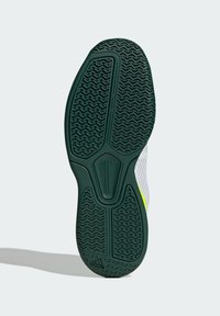 Suola testurizzata verde scuro di una scarpa sportiva con logo Adidas, che mostra i modelli di presa e parte della tomaia bianca e neon.
