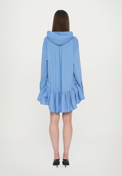 Abito camicia oversized azzurro chiaro con cappuccio, orlo svasato e tessuto testurizzato. Presenta maniche lunghe con dettagli arricciati e hardware minimale.