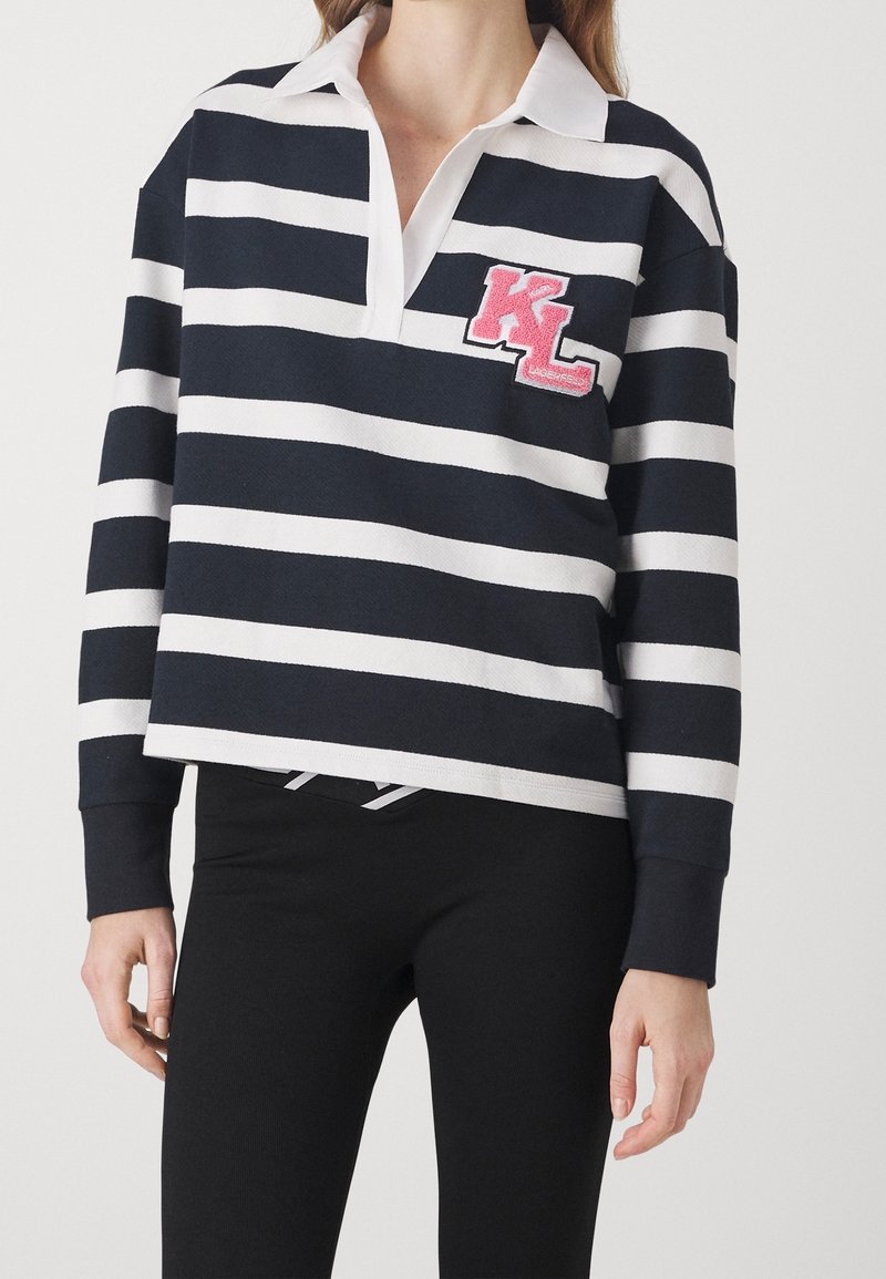 Jersey de rayas azul marino y blanco con un cuello blanco y un logo bordado en rosa "KL" en el pecho. Cuenta con mangas largas y un corte holgado.