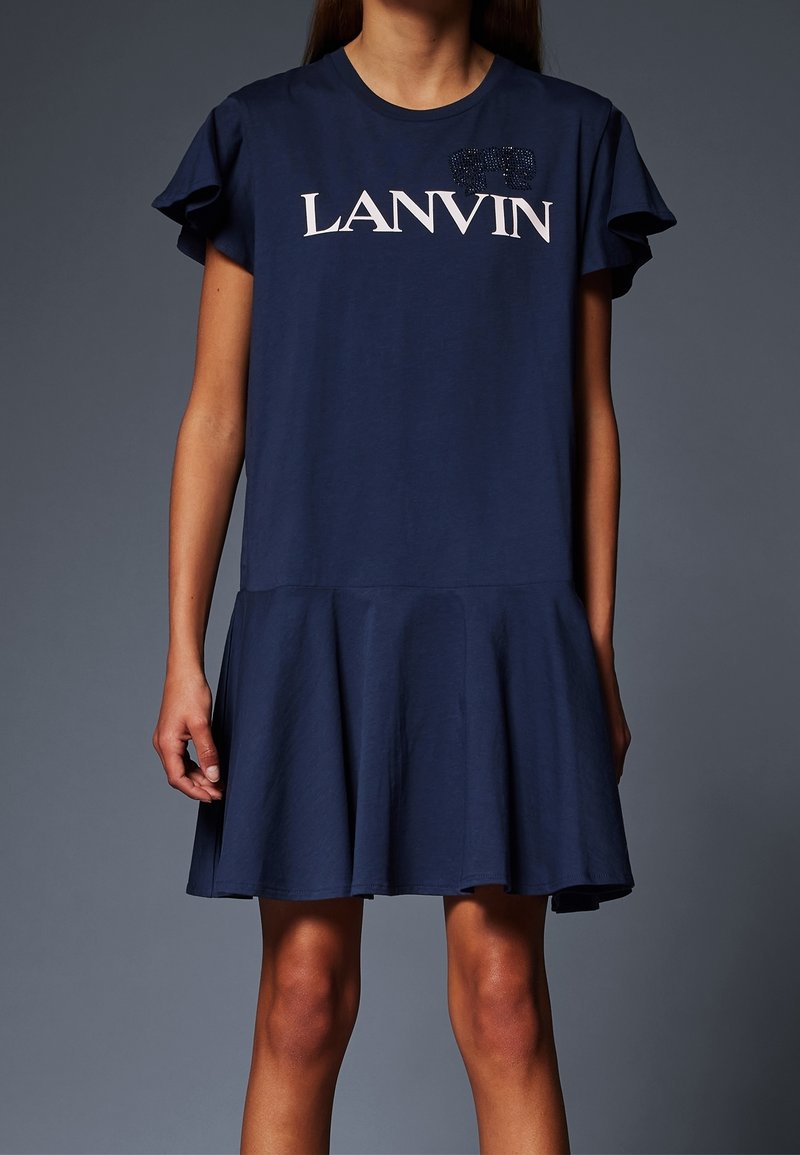 Femme portant une robe bleu marine à manches courtes avec un ourlet évasé et « LANVIN » imprimé en blanc sur la poitrine.