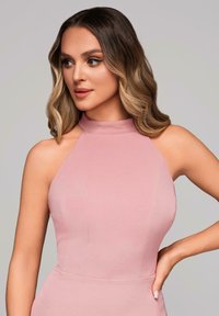 Robe dos nu en tissu rose doux. Design ajusté avec une texture lisse et des détails de couture subtils. Les découpes d'épaules améliorent la silhouette.