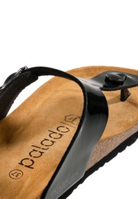 Infradito in pelle nera con soletta in suede e un sottopiede arrotondato. Presenta un dettaglio con bottone e una suola in gomma testurizzata.