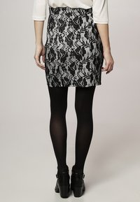 Svart och vit ormtryck mini kjol med en åtsittande design och midjeband, matchad med svarta strumpbyxor och kraftiga klackstövlar.